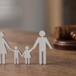 Familienrecht. Figur von Eltern mit Kindern und Hammer auf Holztisch